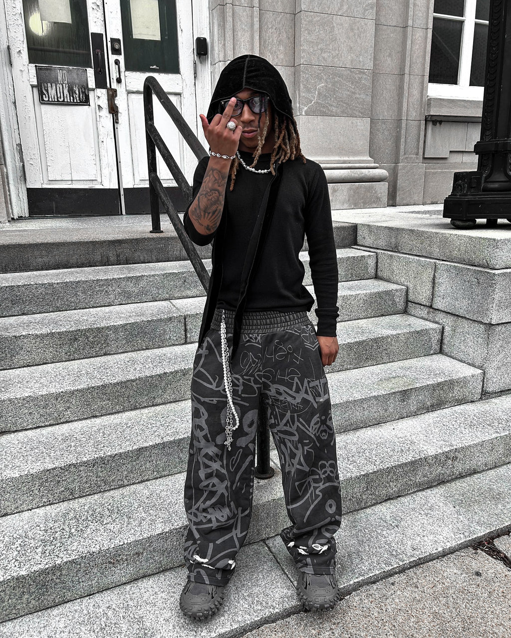 Model wearing Black Vandalizm Sweats on urban steps, showcasing oversized fit and bold graffiti design.